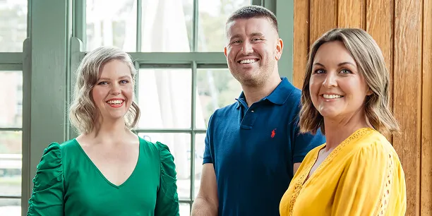 Three Total Wellbeing Diet members smiling, in front of a window.